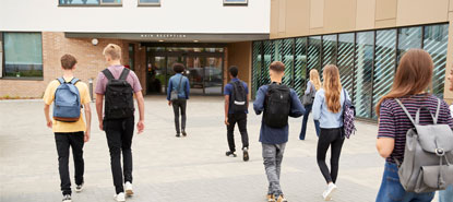 High School students walking into the front of a building