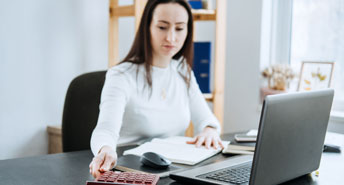 women running one hand thru her hair at a desk. Looking stressed